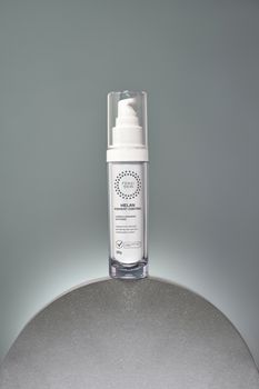 A sleek skincare product bottle on a gray reflective surface, ideal for beauty themes.