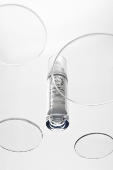 Elegant still life of skincare serum bottle with clear circular overlays and shadows.