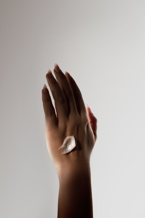 Free Close-up of a hand with moisturizing cream under soft light emphasizing skincare and self-care. Stock Photo