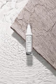 Elegant skincare product displayed on a textured surface with rippling water effect.
