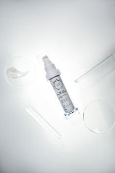 High-angle view of a cosmetic serum with glass lab equipment, showcasing clean and modern design.