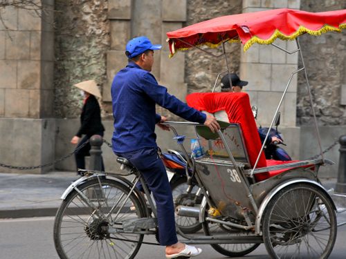 Free Image of a man riding a cyclo through the bustling streets of Hanoi, Vietnam. Stock Photo