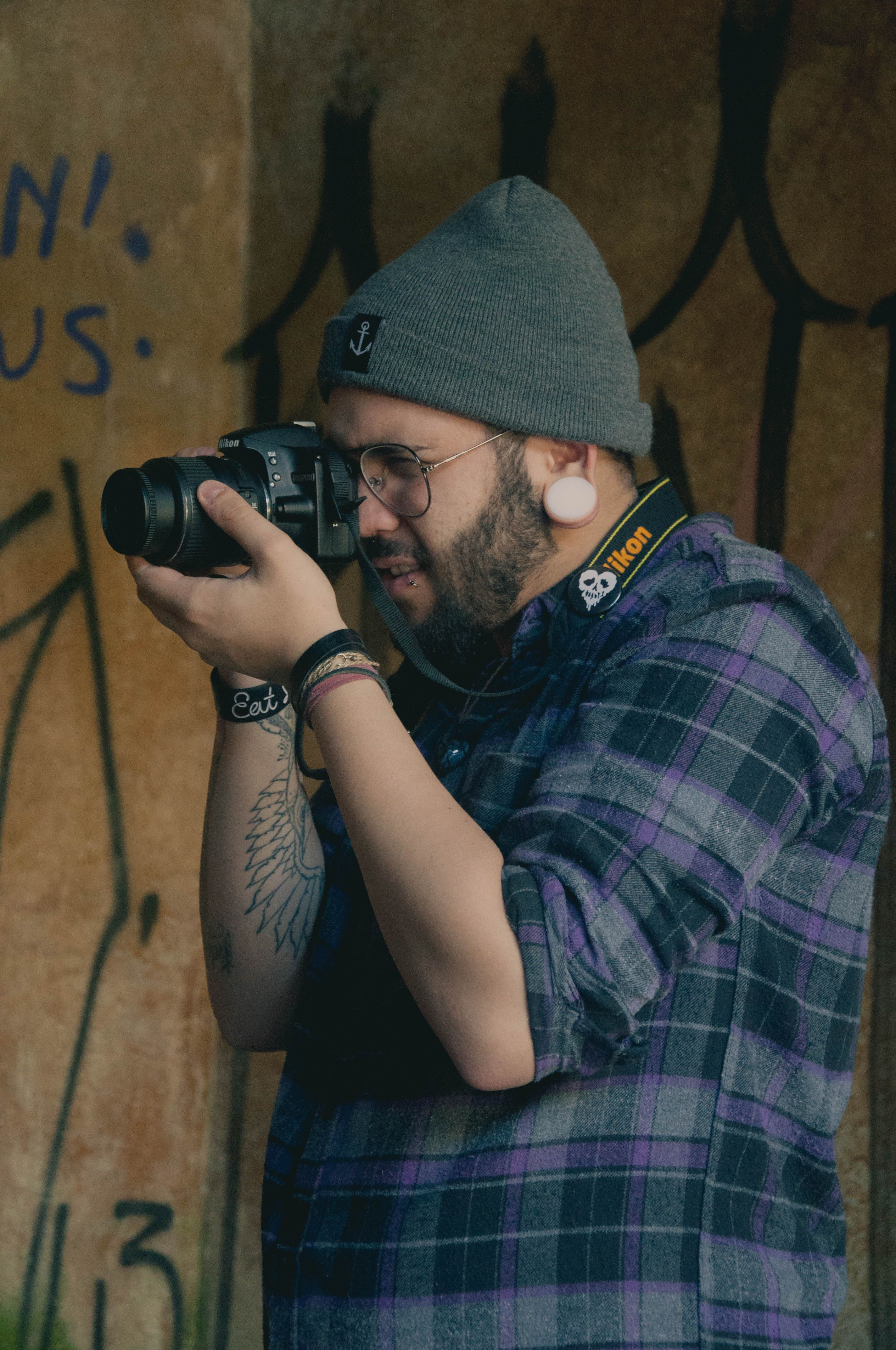 Casual photographer against urban graffiti capturing moments outdoors.