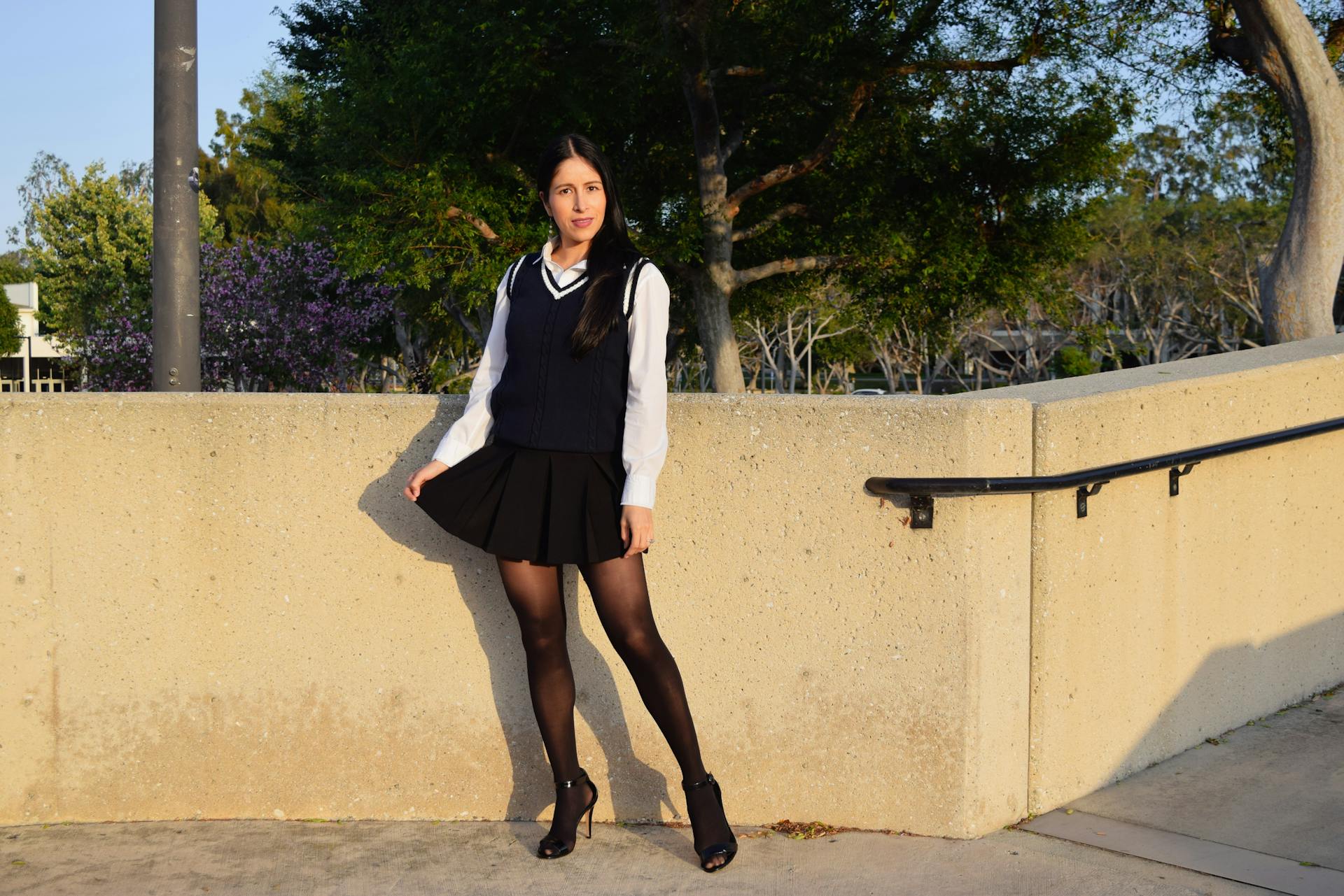 Woman in fashionable attire poses in a sunny Long Beach park, embracing urban style.
