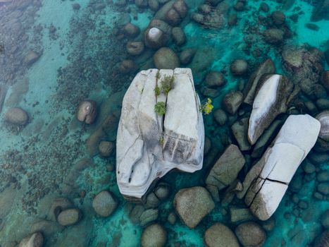 Aerial shot of large rocks in transparent turquoise water, showcasing natural beauty.