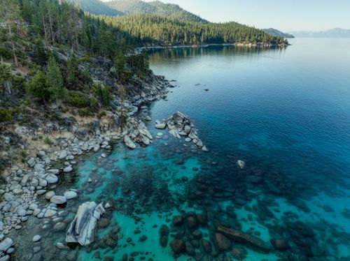 Free Aerial view of Lake Tahoe's tranquil coastline, showcasing crystal-clear waters and forested landscape. Stock Photo