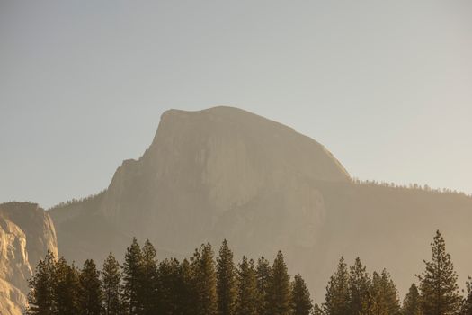 Serene image of Half Dome in Yosemite with a misty sunrise backdrop, showcasing nature's beauty.