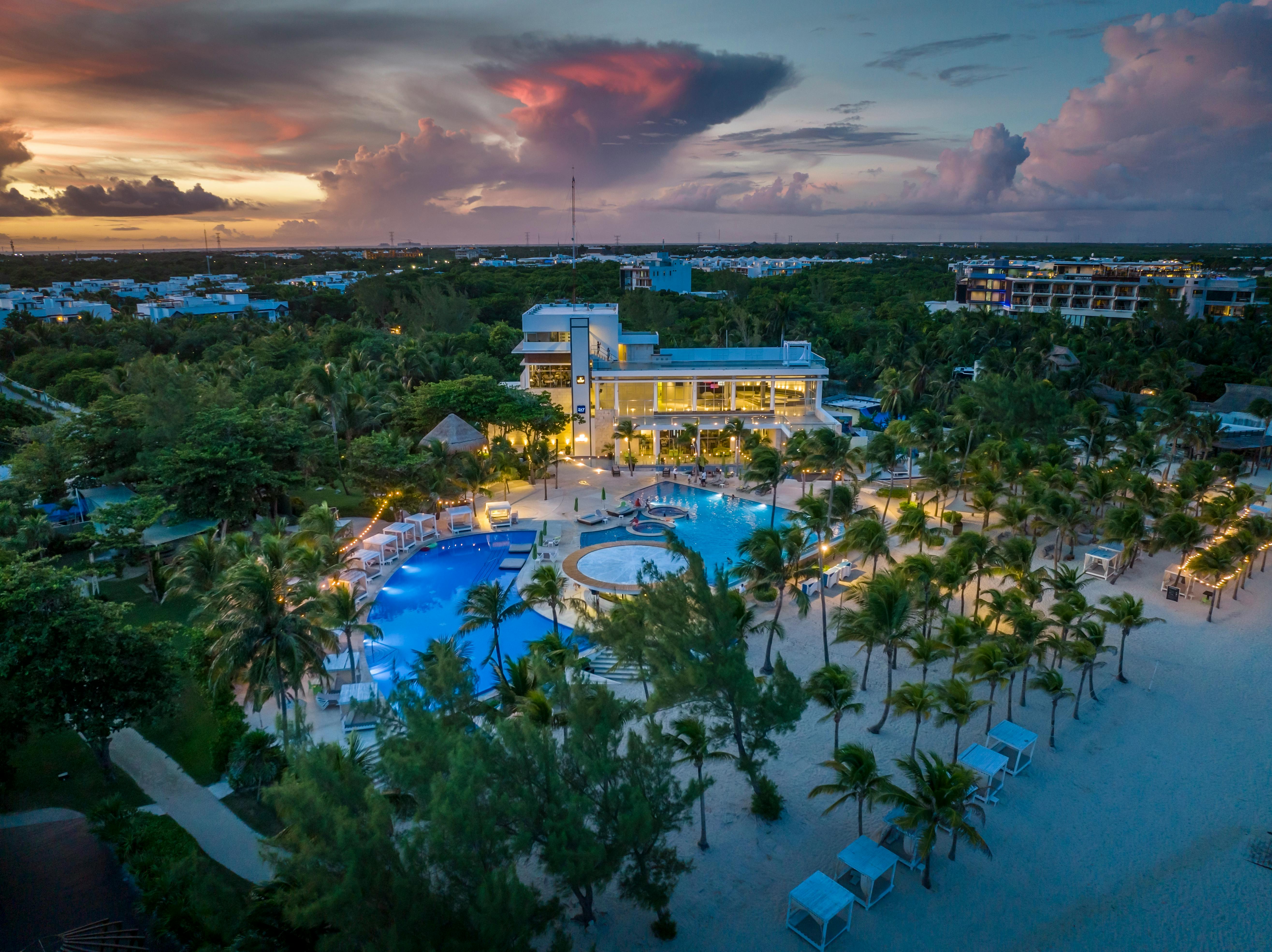 Aerial view of a stunning beach resort in Playa del Carmen at sunset, showcasing vibrant skies and luxurious amenities.
