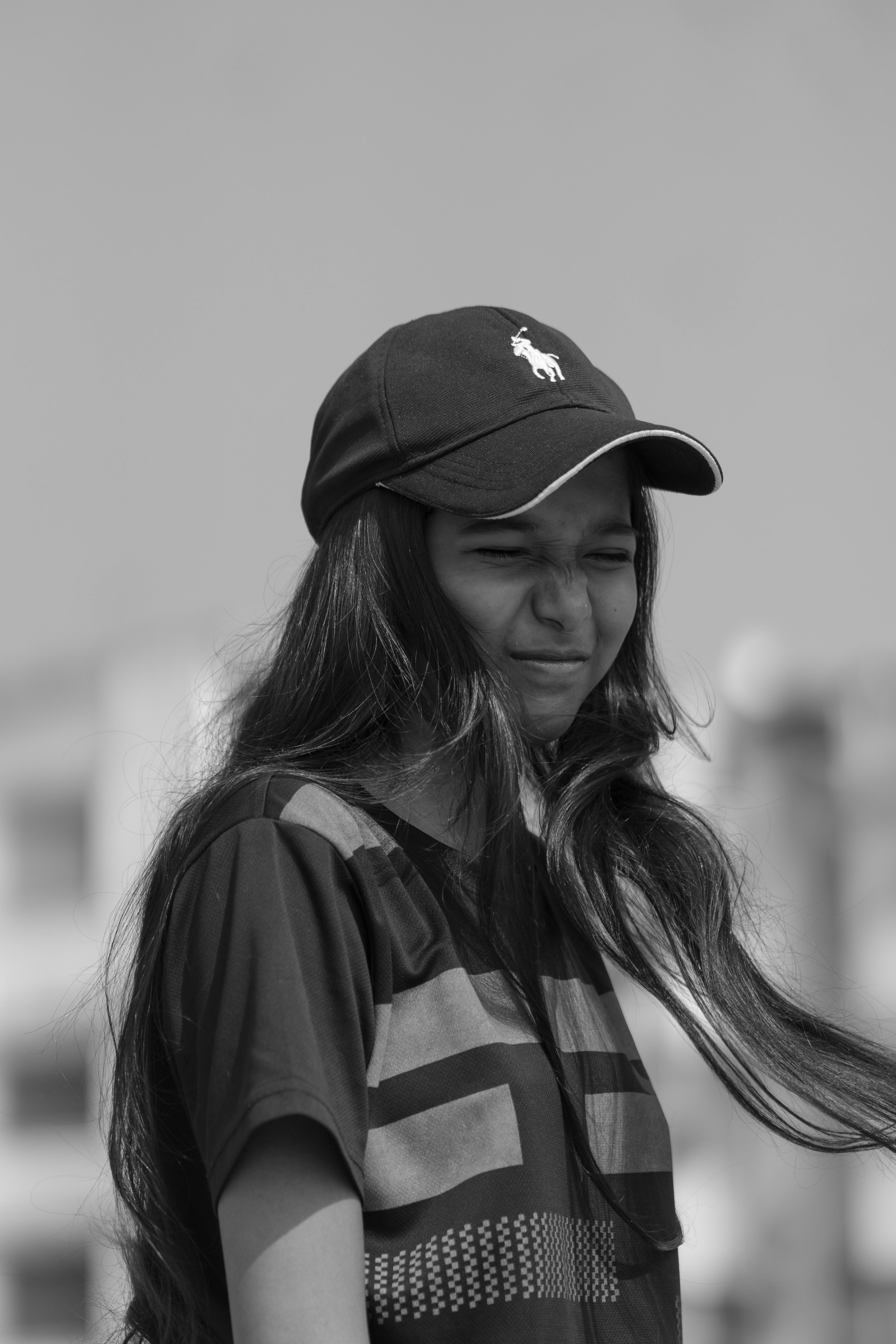 a black and white photo of a girl wearing a hat