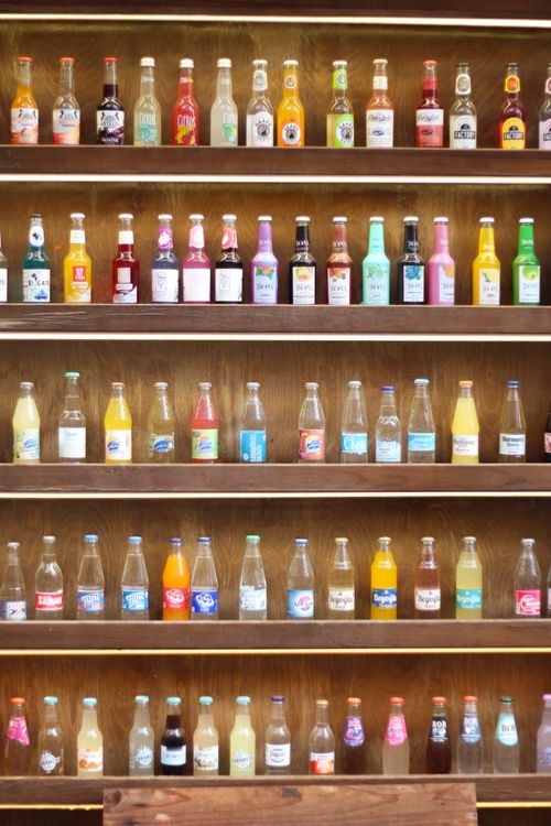 Free A vibrant collection of assorted beverage bottles neatly arranged on wooden shelves, showcasing various colors and brands. Stock Photo