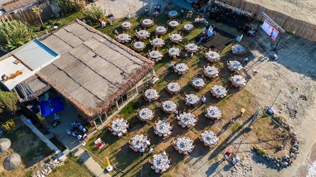 Aerial capture of elegant outdoor wedding setup on a sandy beachfront in Çeşme, Türkiye.