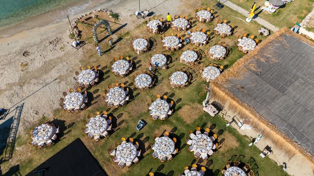 Aerial shot of elegant round tables set up for a beach wedding in Çeşme, Türkiye.