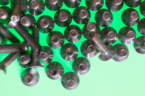Free Close-up of metallic screws on a vibrant green surface, symbolizing technology and industry. Stock Photo