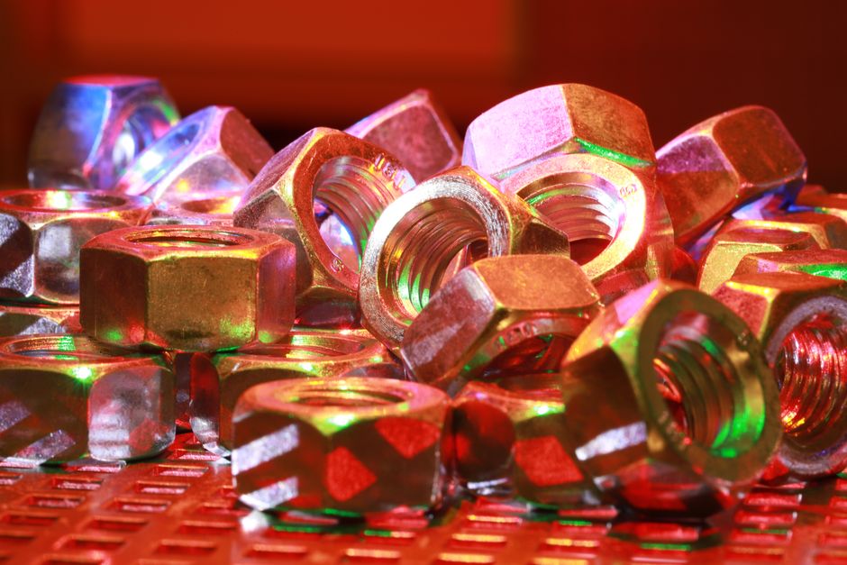 Close-up of metallic hex nuts with vibrant multicolored reflections. Perfect for industry theme.