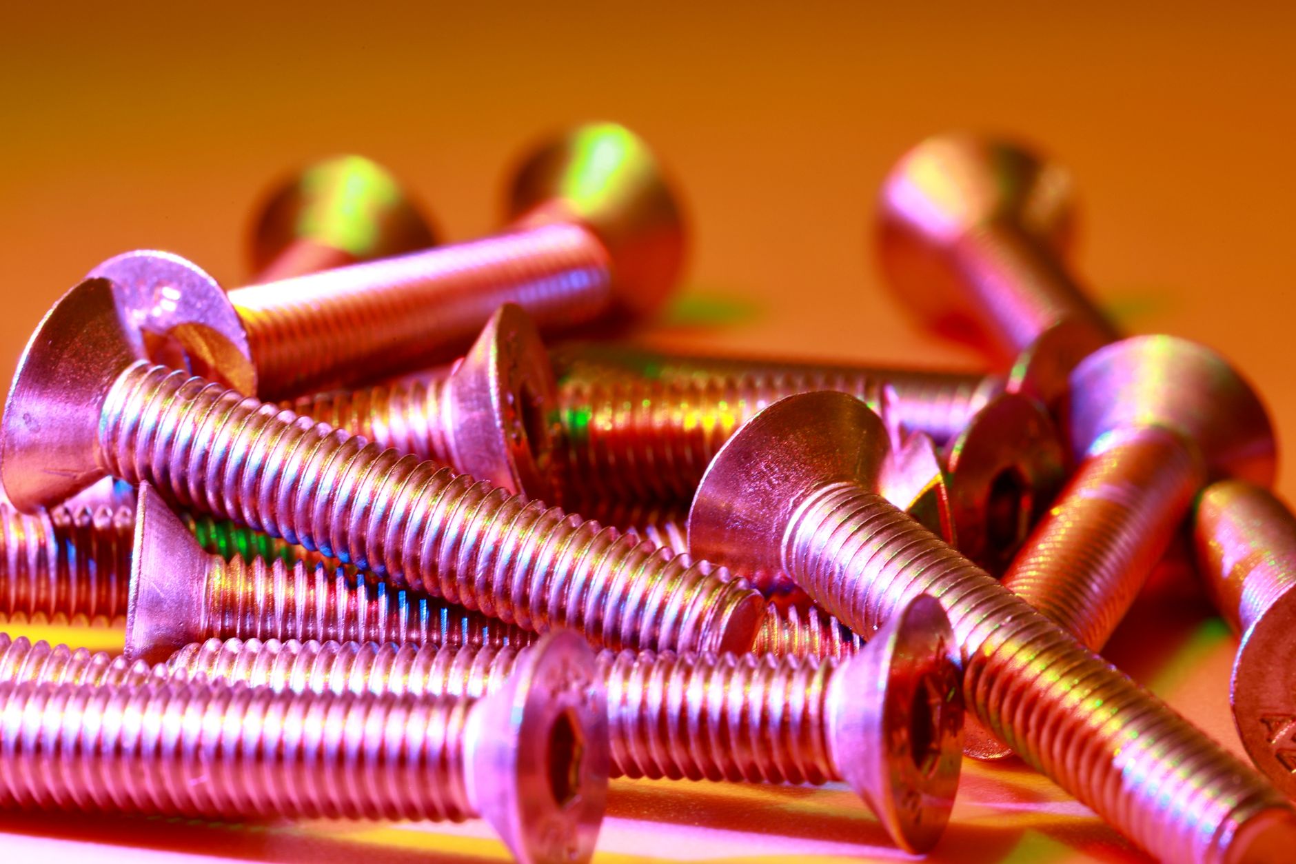 Vibrant macro shot of colorful metallic screws arranged in an artistic manner.