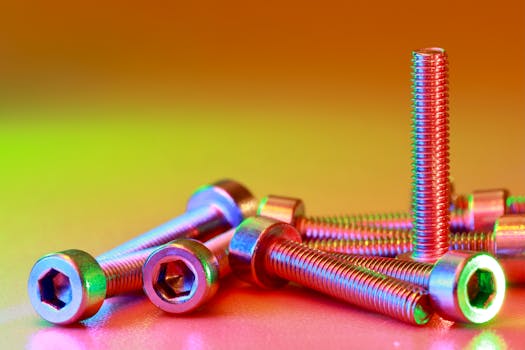 Vibrant close-up of chrome bolts with hexagonal heads on a colorful background.