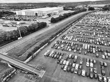 Aerial perspective of a large car park beside an industrial warehouse in England.