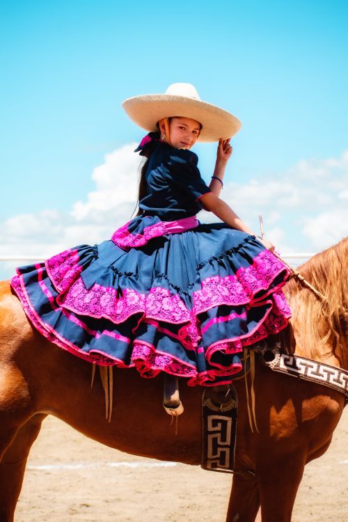 Free A girl in colorful traditional attire on horseback in a sunny outdoor setting. Stock Photo