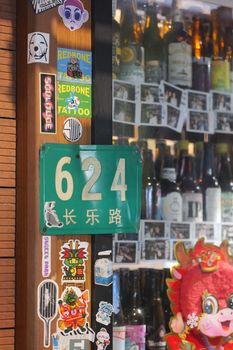 Street view of a bar with unique stickers and Chinese address sign.