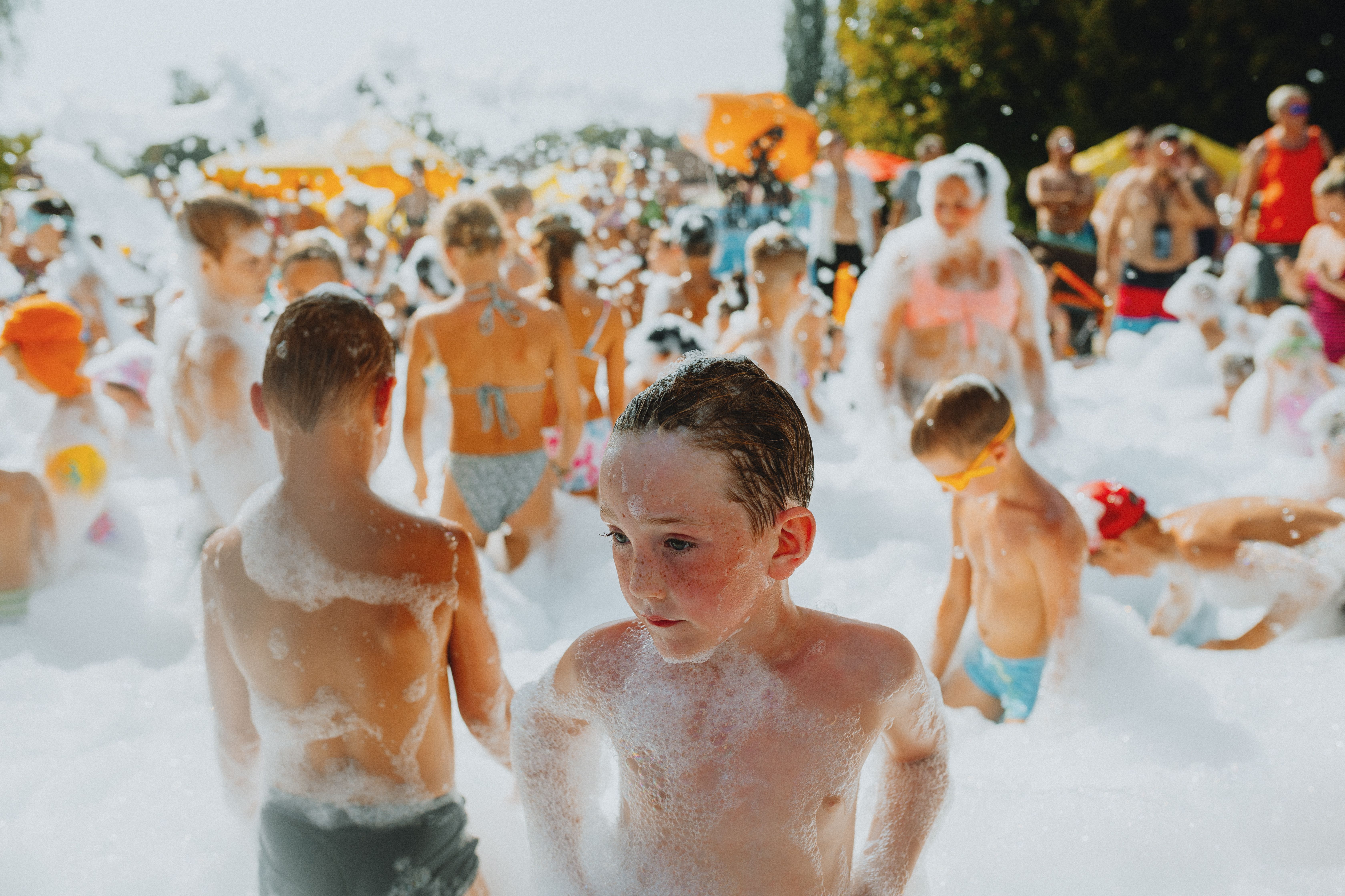 foam party organizer egypt — A cheerful group of children playing in a lively outdoor foam party on a sunny day.