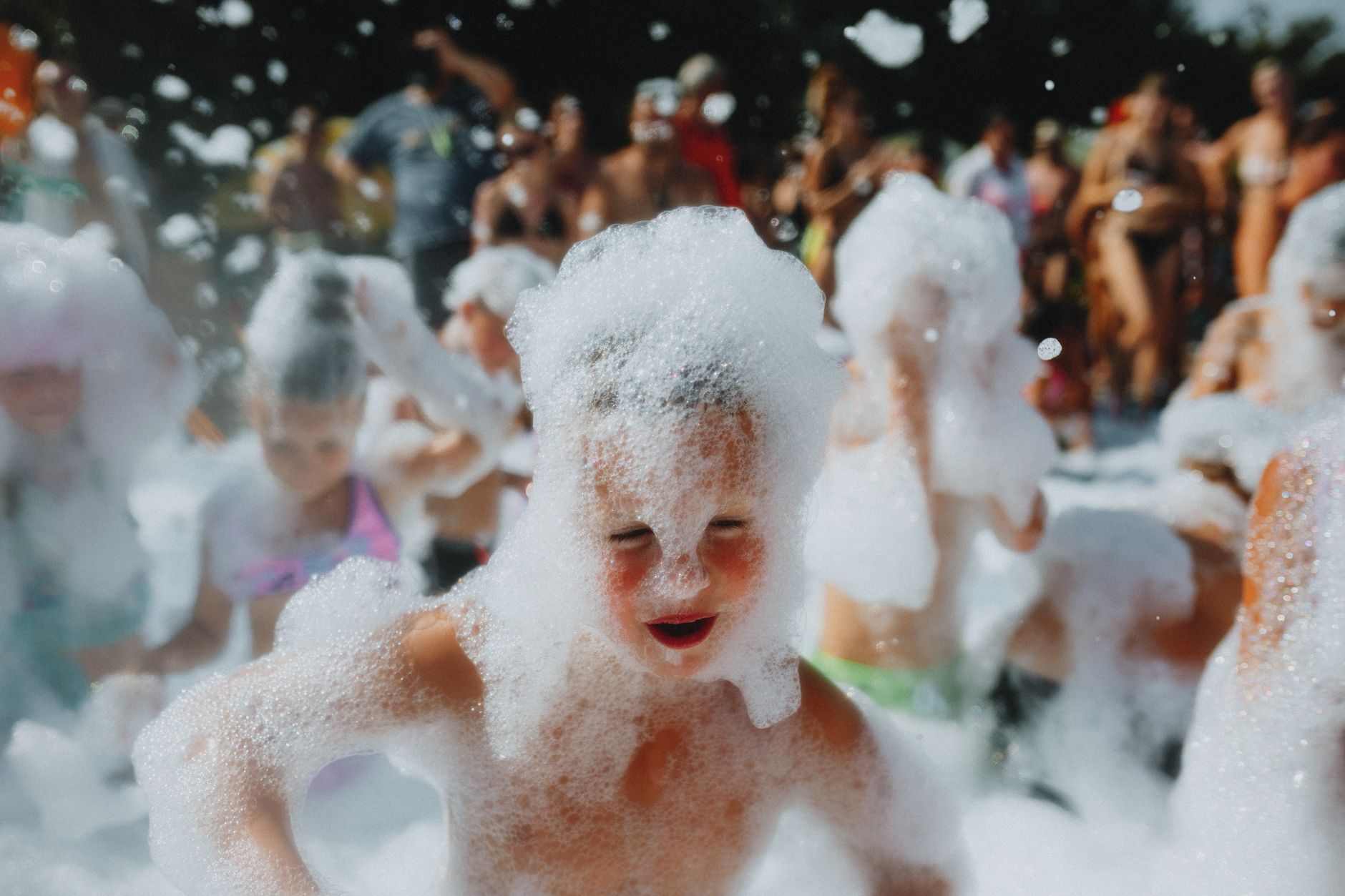 foam party organizer egypt — Kids having fun in a lively foam party, enjoying bubbles and sunshine outdoors.