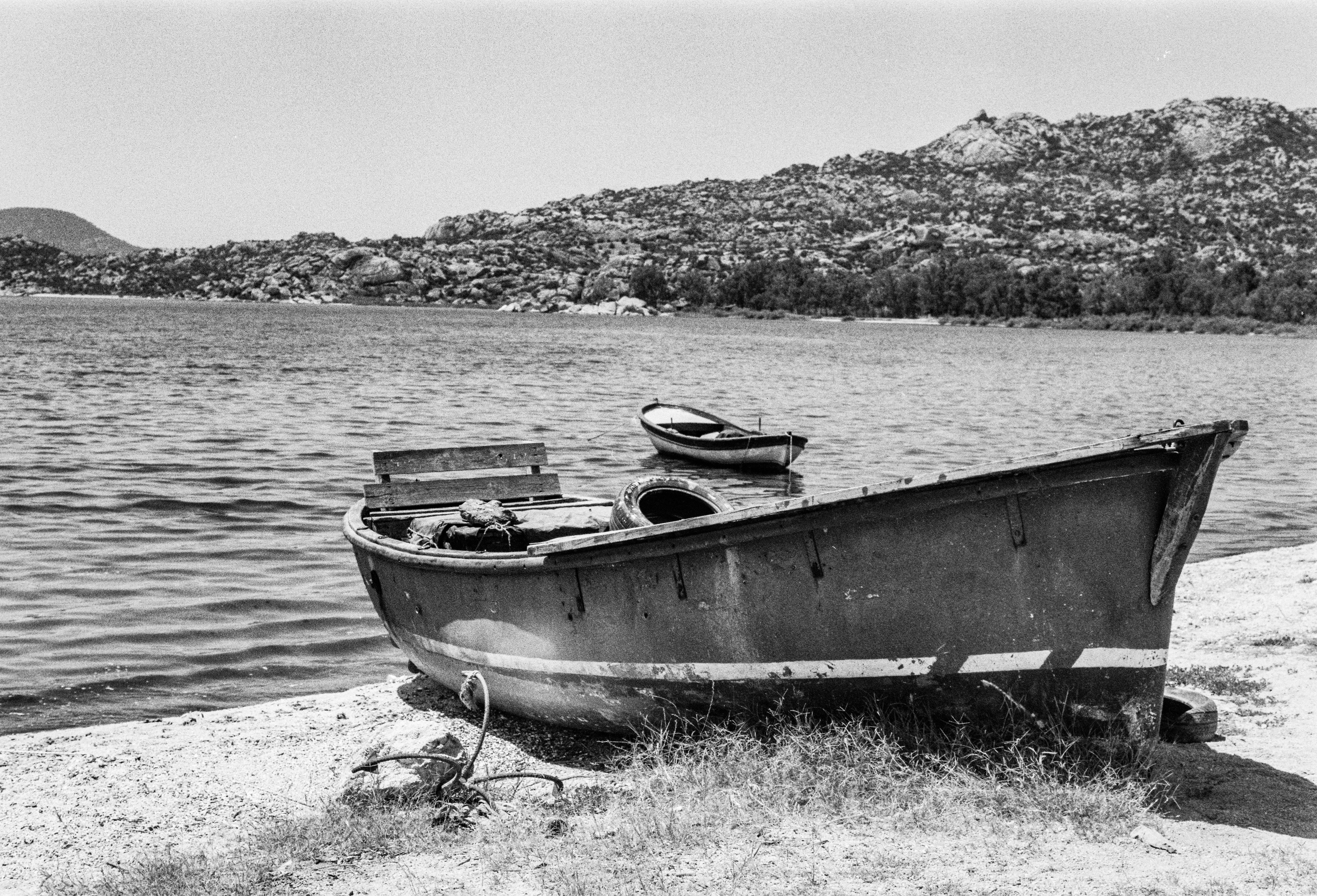 A vintage rowboat rests on the tranquil lake shore with distant mountains in Türkiye.