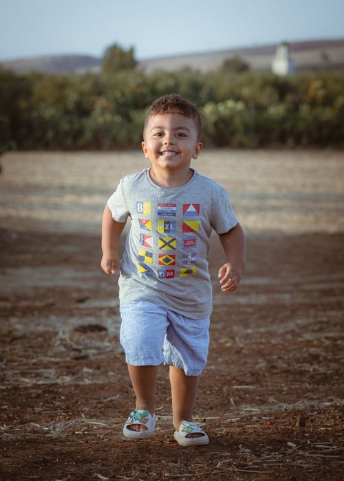 Free Joyful young boy in casual attire running on a sunny day, depicting happiness and freedom. Stock Photo