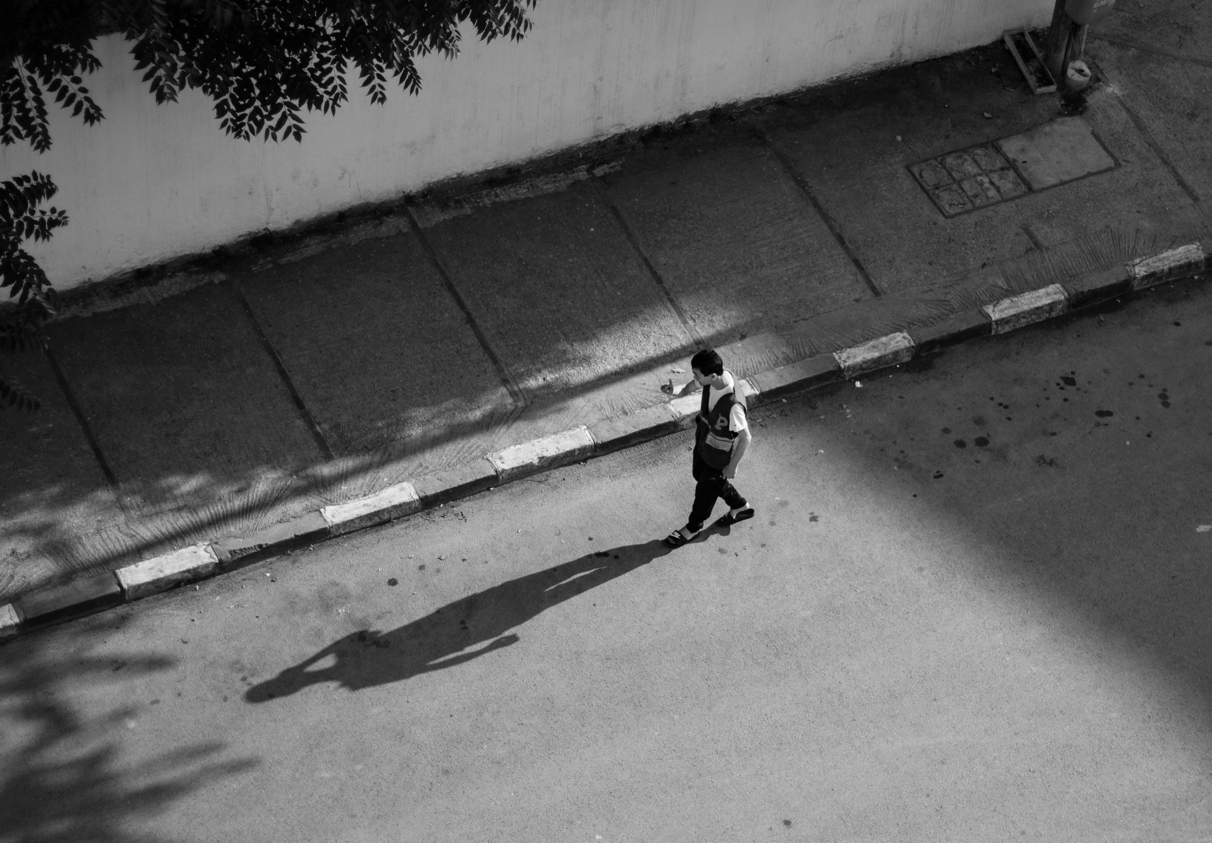 A man walking down the street with his shadow · Free Stock Photo