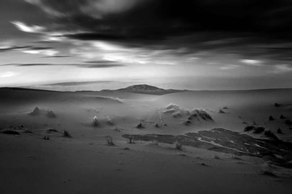 Stunning black and white photo of a desert landscape at twilight with dramatic sky.