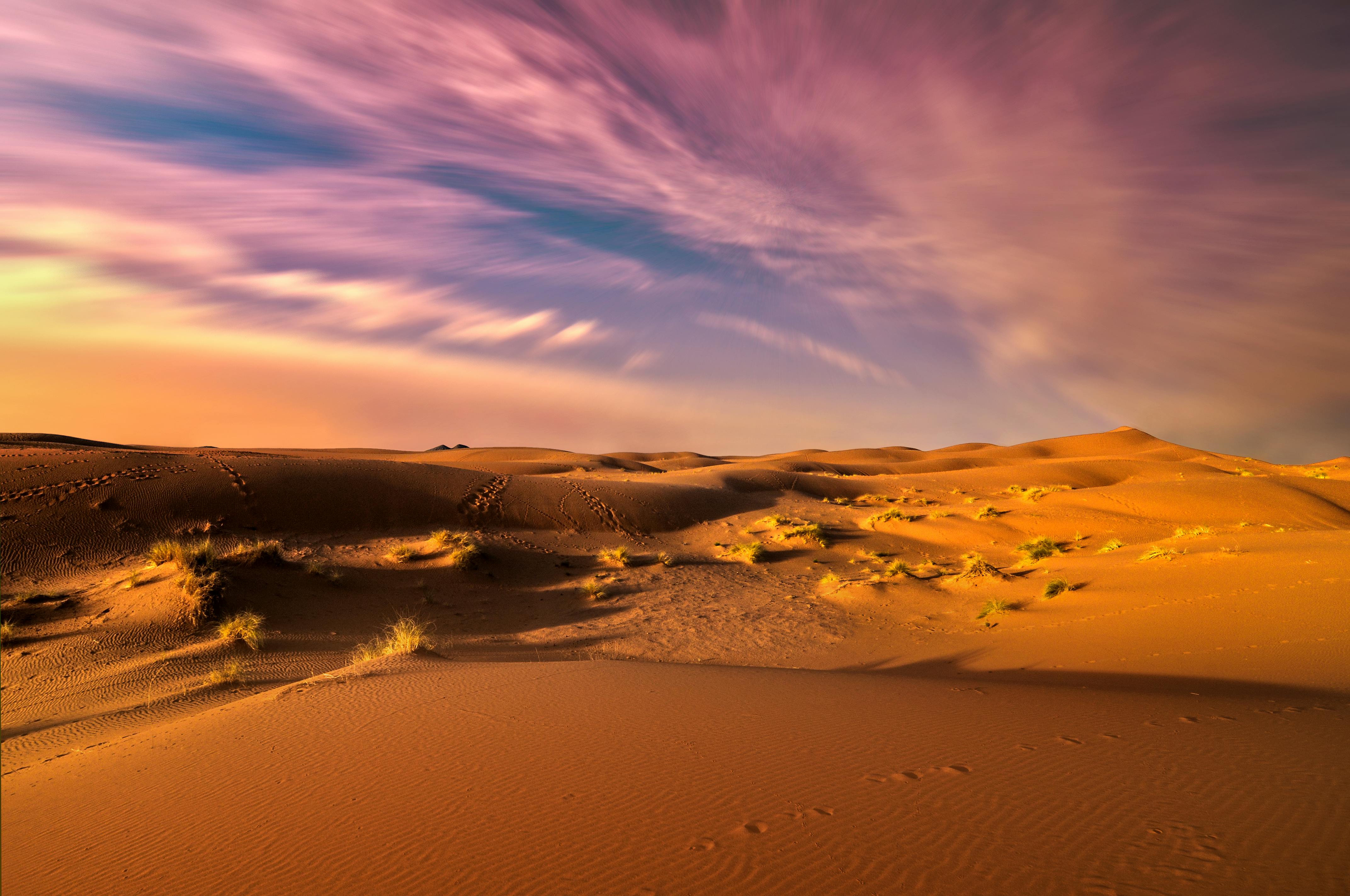 Stunning desert landscape with golden dunes and colorful sunset sky.