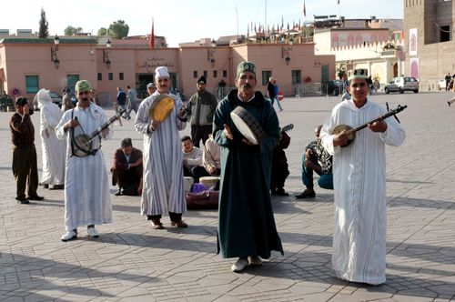 Free Musicians in traditional attire performing with instruments on a Moroccan street. Stock Photo