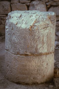 Historic stone pillar with Latin inscriptions found in Jendouba, Tunisia, showcasing ancient architecture.