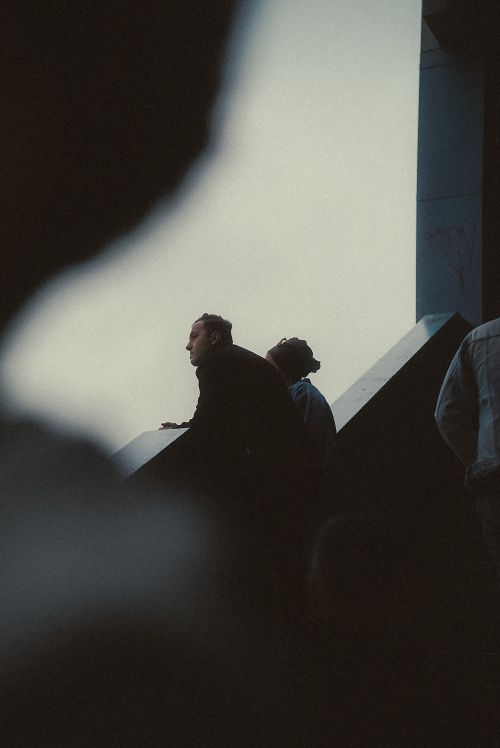 Free A contemplative couple looks out from a city building edge, capturing a thoughtful moment. Stock Photo