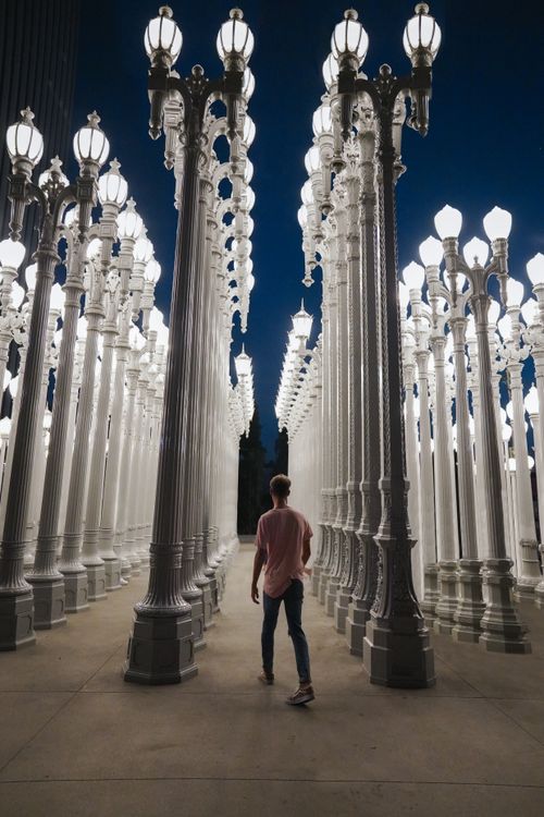 Free A man walks through the illuminated Urban Light installation in Los Angeles at night. Stock Photo
