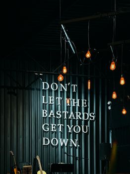 Hanging light bulbs illuminate motivational quote against a dark backdrop.