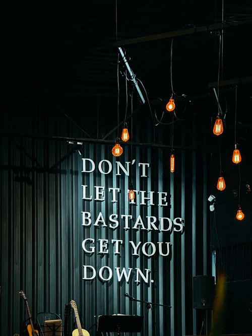 Free Hanging light bulbs illuminate motivational quote against a dark backdrop. Stock Photo