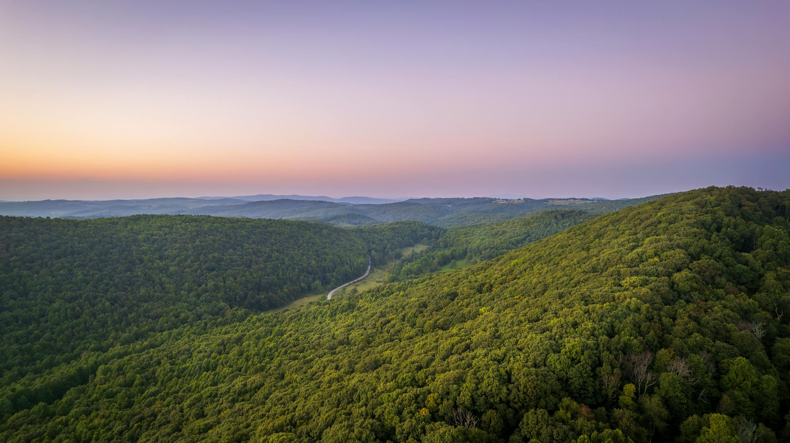 free photo of a scenic view of the mountains and forest at sunset