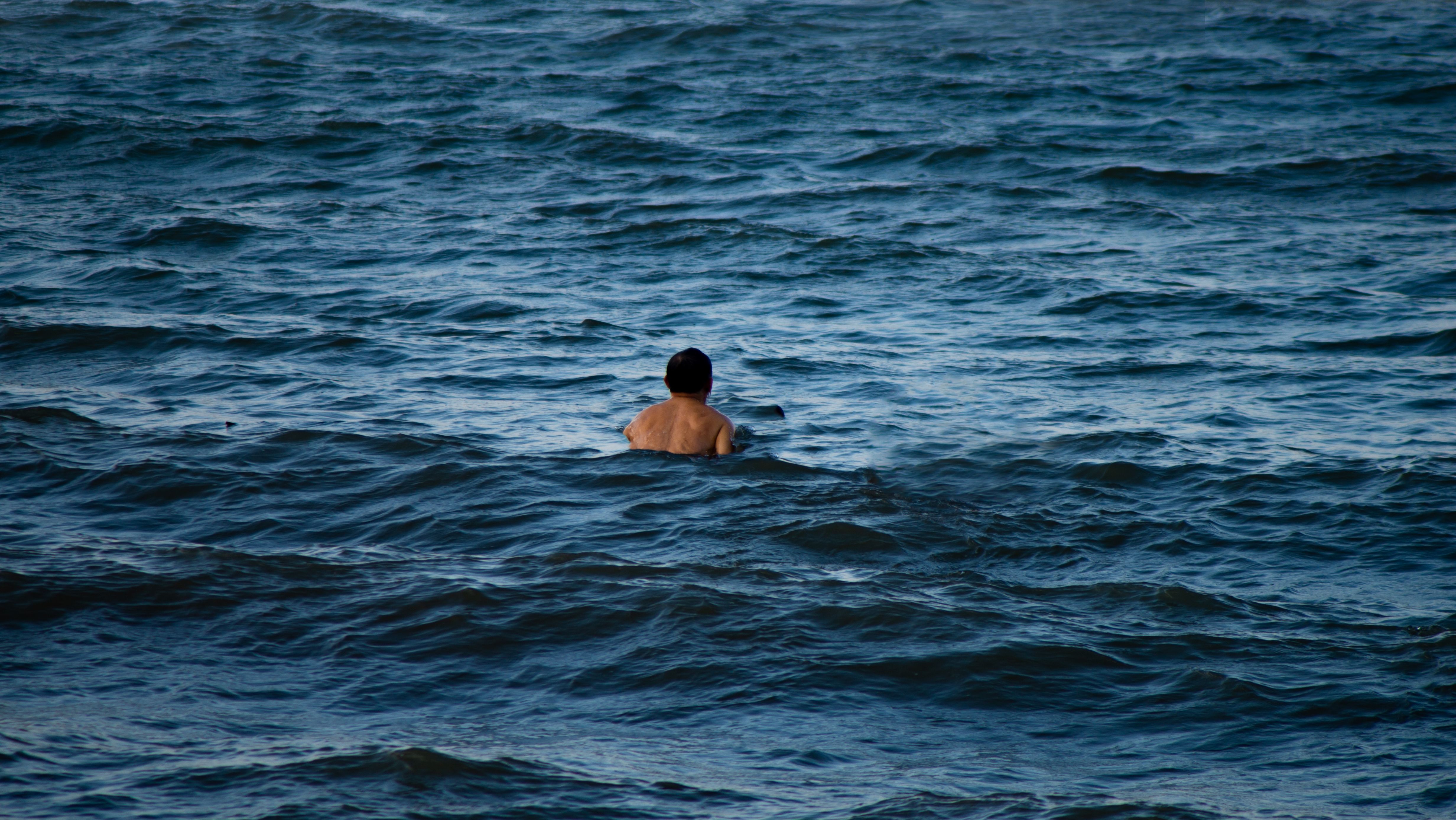 A lone swimmer immersed in the vast ocean waters enjoying the serene waves.
