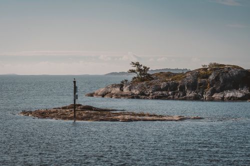 Free Peaceful seascape with a small rocky island and calm waters, perfect for travel inspiration. Stock Photo