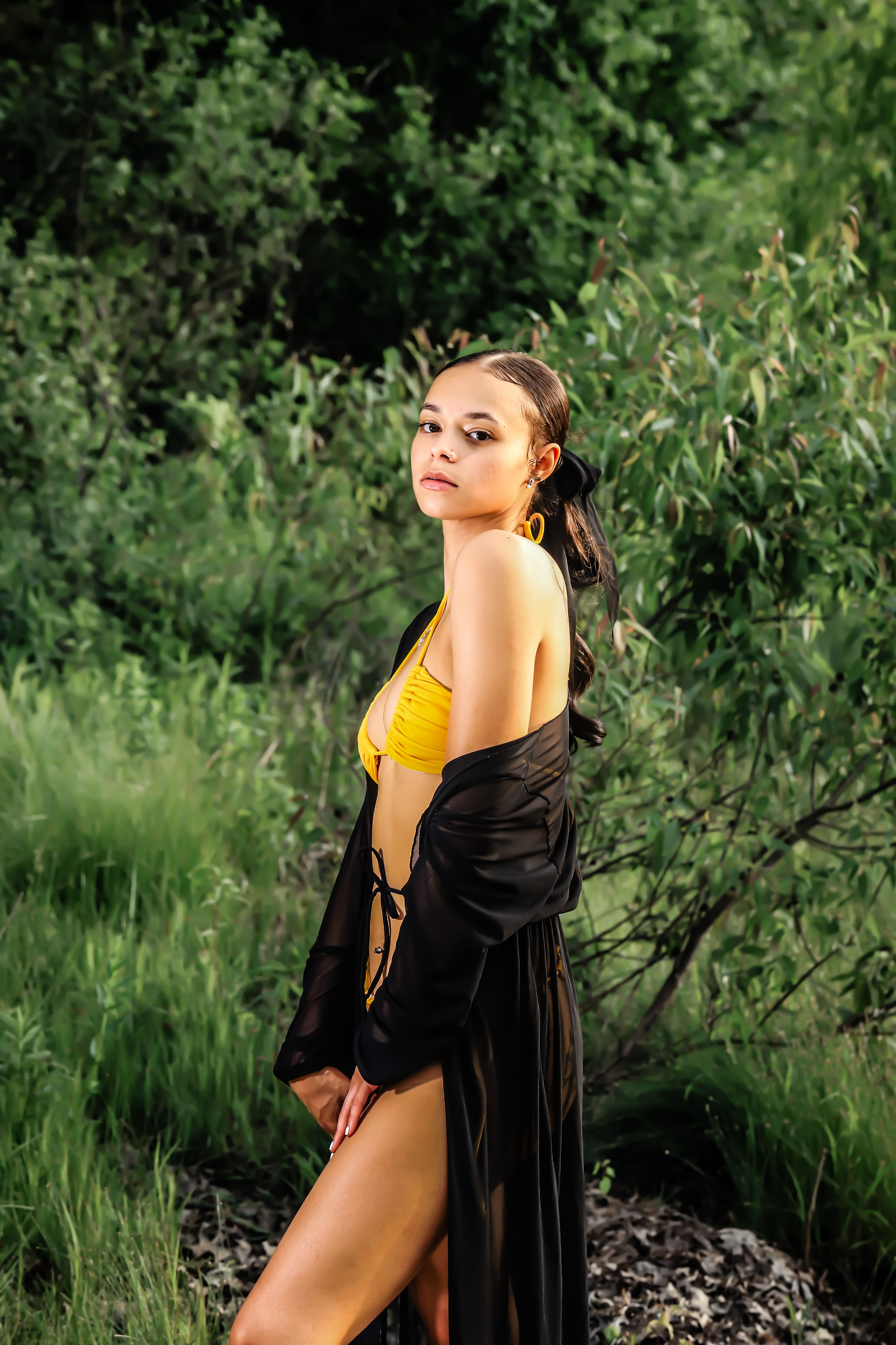 A young woman in a yellow bikini posing confidently outdoors, exuding summer fashion vibes.