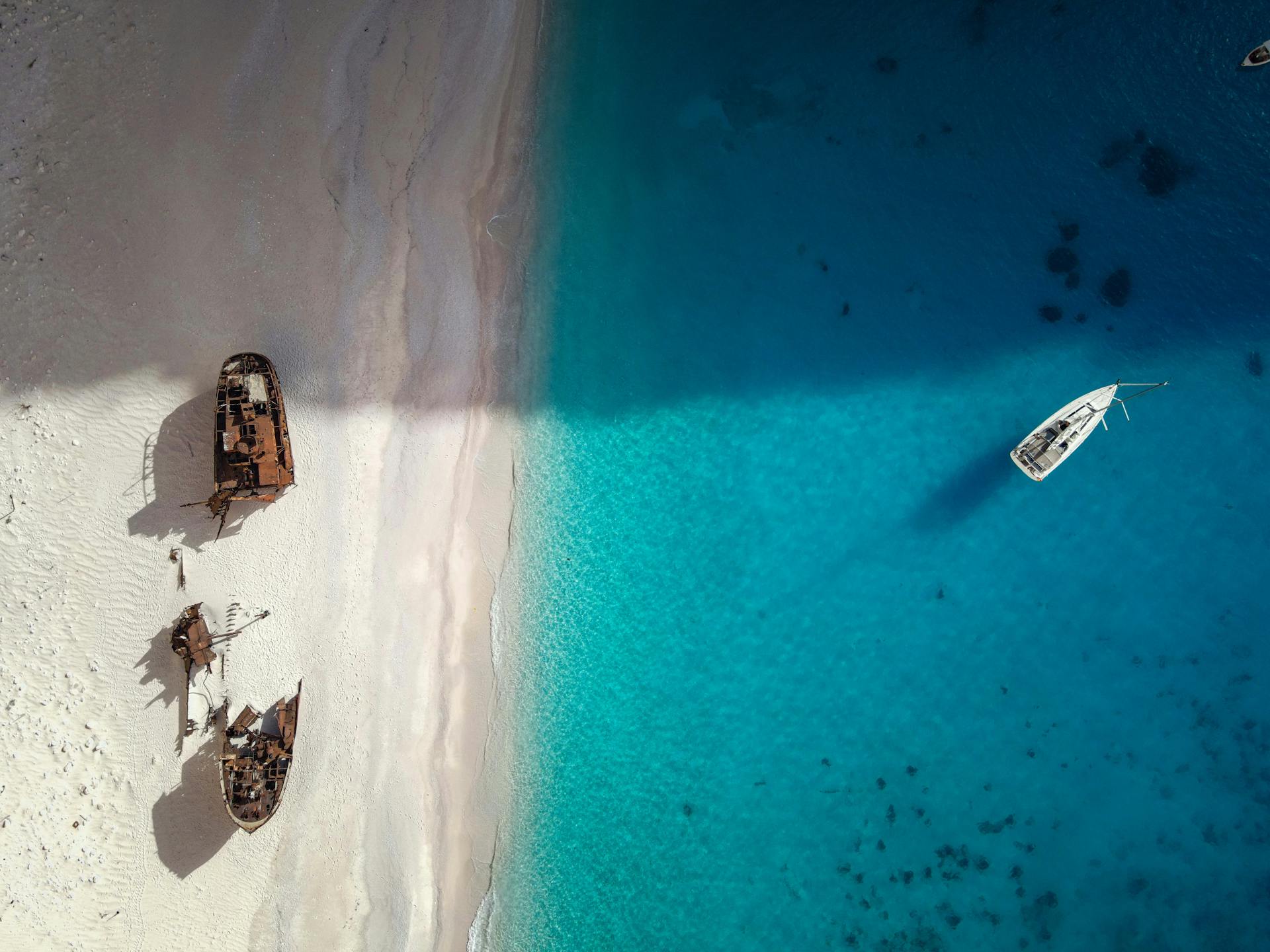 A stunning aerial shot of a shipwreck on a pristine beach with vibrant blue water.