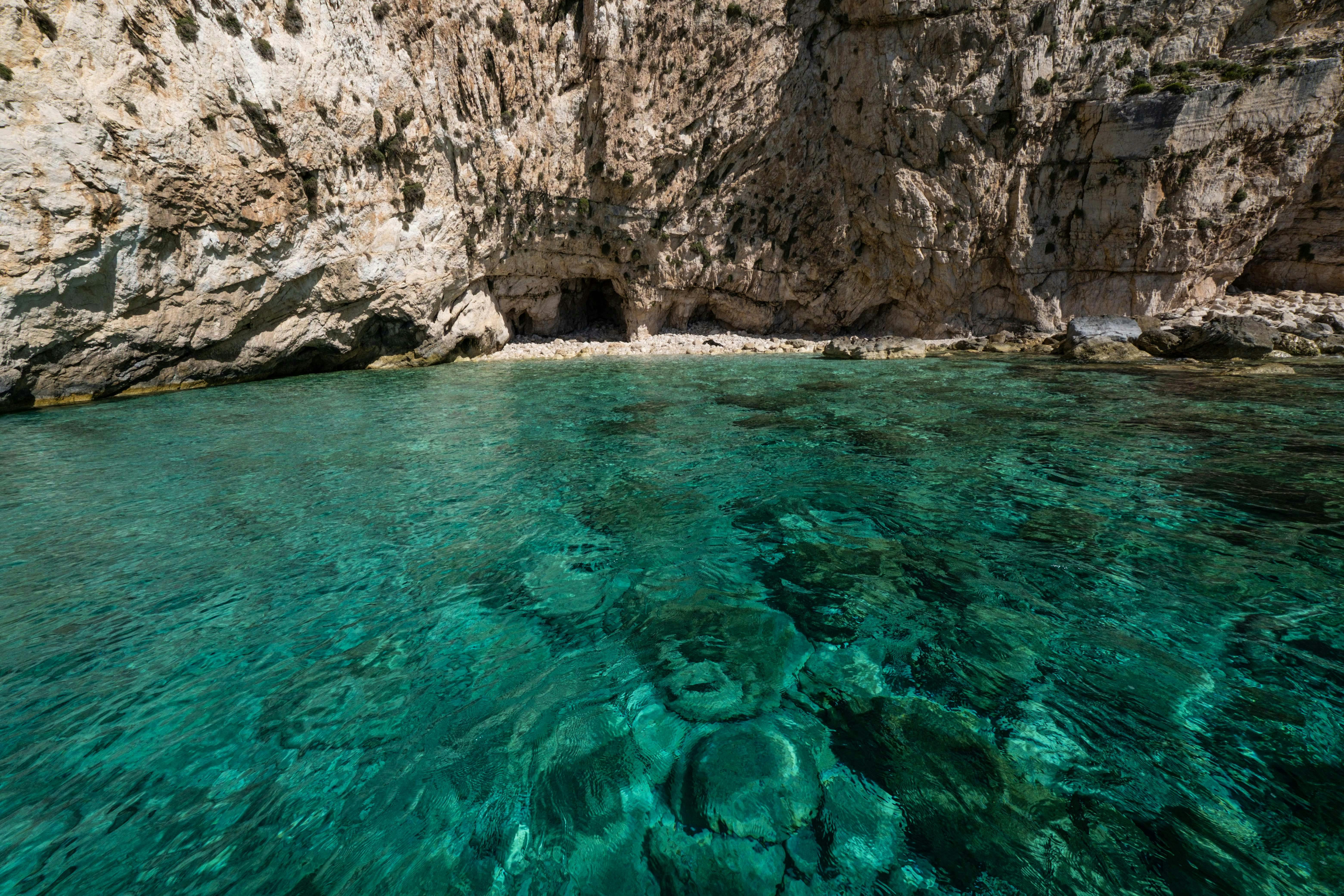 Stunning turquoise waters by rocky cliffs, ideal for tropical vacation settings. - Photo by Francesco Ungaro on Pexels