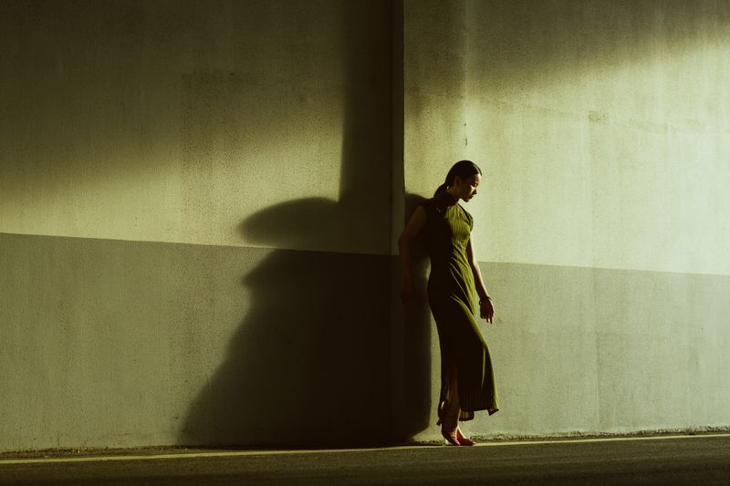 A woman in a long dress leaning against a wall · Free Stock Photo