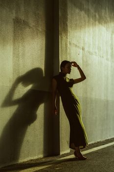 Artistic photo of a woman silhouetted against a sunlit wall.