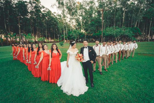 A well-coordinated wedding party poses outdoors with bridesmaids and groomsmen in matched attire.