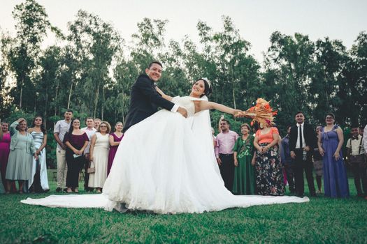 Happy couple celebrating their wedding outdoors with friends and family.
