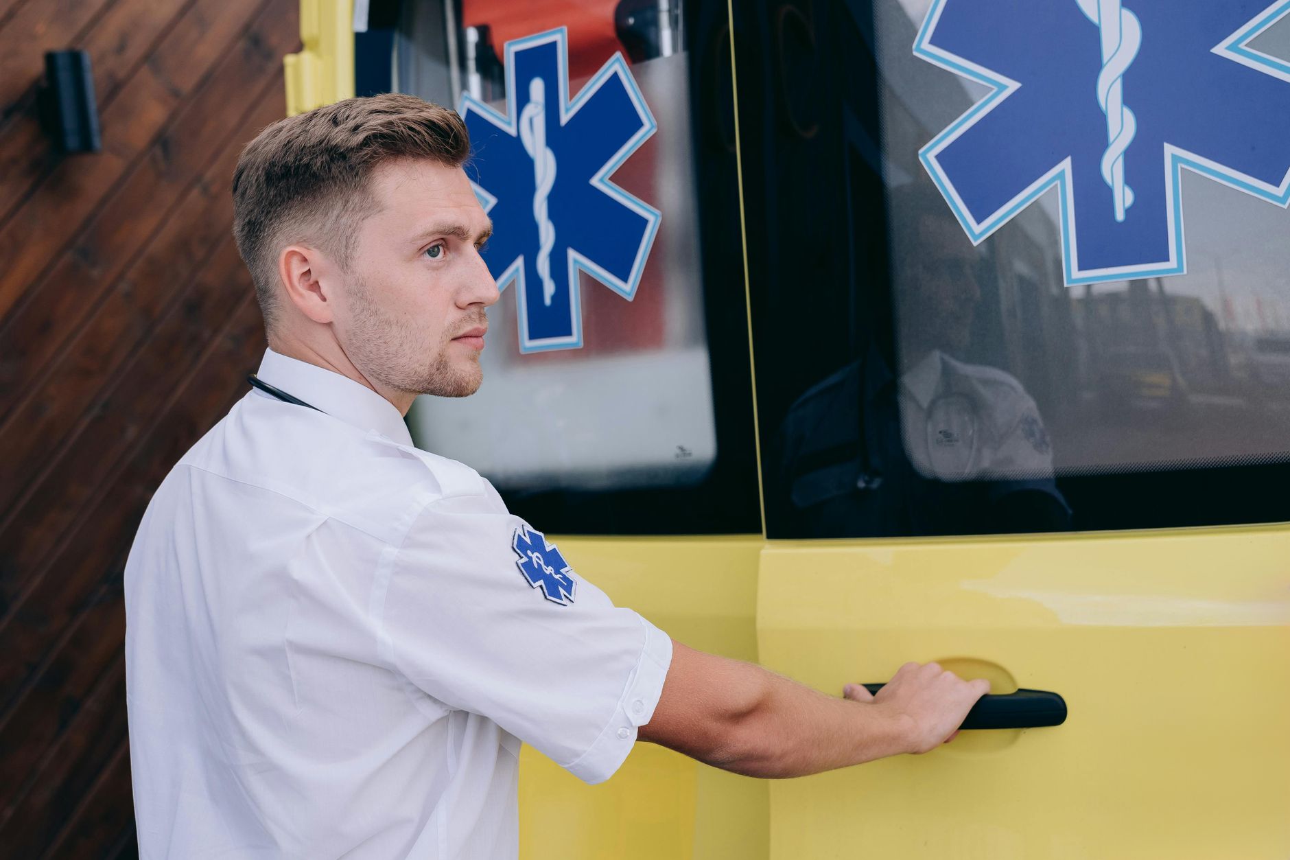 A focused paramedic opens the rear door of an ambulance, ready for emergency services.