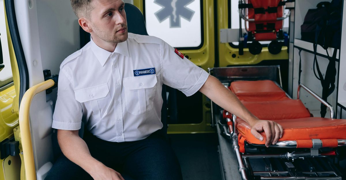 Paramedic Sitting at the Back of an Ambulance by the Gurneys · Free ...