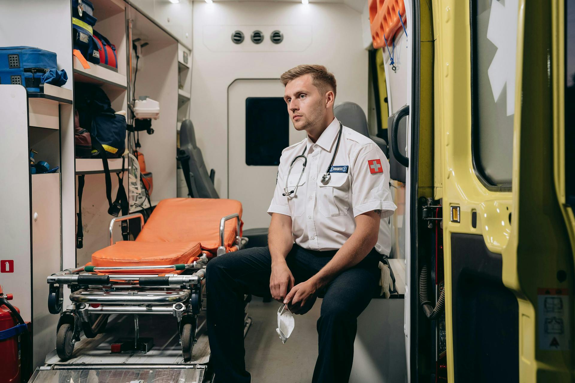 Paramedic Sitting in an Ambulance with a Face Mask in His Hands