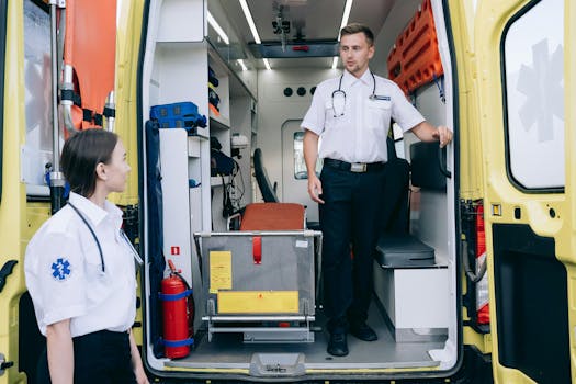 Two paramedics in uniforms and stethoscopes preparing ambulance for upcoming medical emergencies.